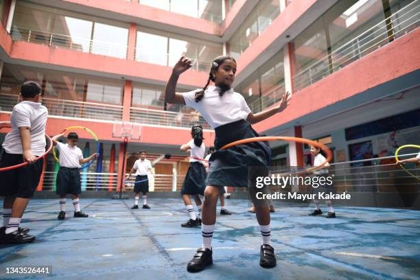 school girls playing plastic hula hoop in school courtyard - indian society and daily life ストックフォトと画像