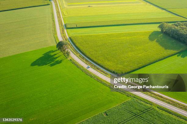 aerial photo of car on a road on an agricultural area - car country road stock-fotos und bilder
