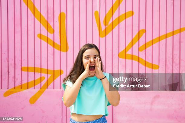 young girl shouting with summer clothes in front of pink background with arrows pointing her. - slogan pattern fotografías e imágenes de stock