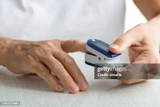 senior woman using oximeter - pulse oximeter stockfoto's en -beelden