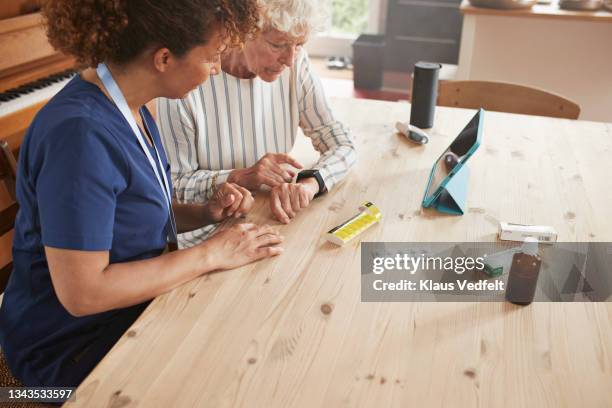 woman learning to use smart watch from caregiver - wearables photos et images de collection