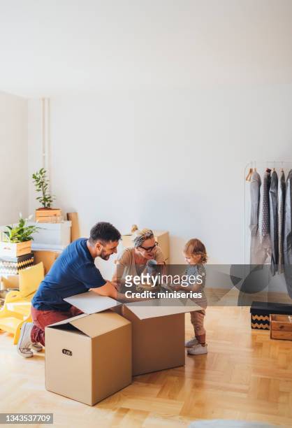 cheerful family moving in new home - unpacking stock pictures, royalty-free photos & images