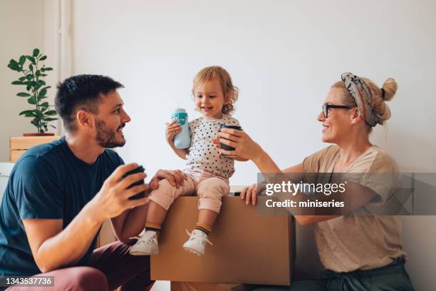 familia joven celebra mudarse en un nuevo hogar - baby cup fotografías e imágenes de stock