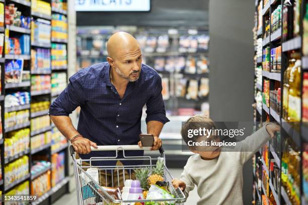 shot of a man shopping for groceries with his son in a supermarket - mini grocery store stock pictures, royalty-free photos & images