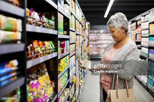 aufnahme einer reifen frau, die in einem supermarkt lebensmittel einkauft - grocer stock-fotos und bilder