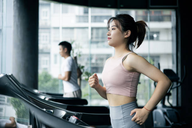 トレッドミルで走る若い女性 - ジム 女性 日本人 ストックフォトと画像