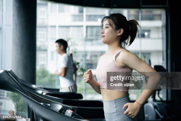 トレッドミルで走る若い女性 - トレッドミル　女性 ストックフォトと画像