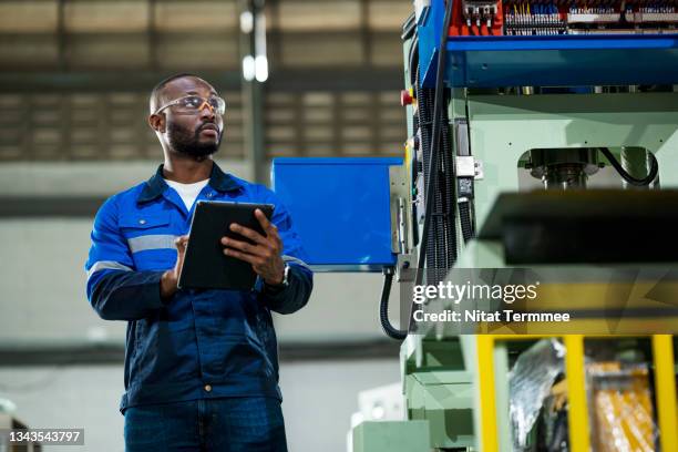 analyzing the machine utilization and overall equipment effectiveness of machinery. african industrial engineer holding a digital tablet for monitoring performance to forecast, planning of machine workload. - maintenance engineer stock pictures, royalty-free photos & images