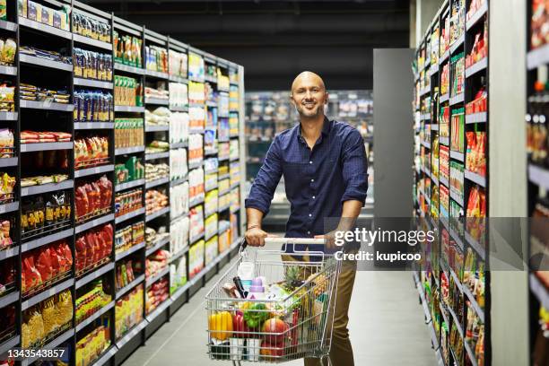 shot of a man shopping for grocery in a supermarket - man pushing stock pictures, royalty-free photos & images