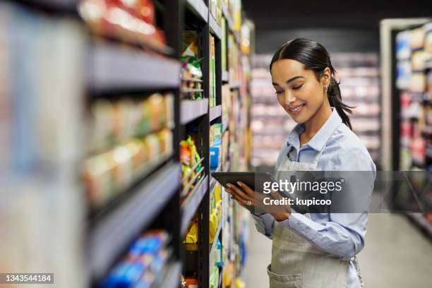 foto de una mujer joven usando una tableta en el trabajo en un supermercado - supermercado fotografías e imágenes de stock