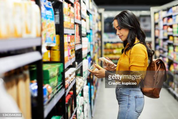 shot of a young woman shopping for groceries in a supermarket - shop stockfoto's en -beelden