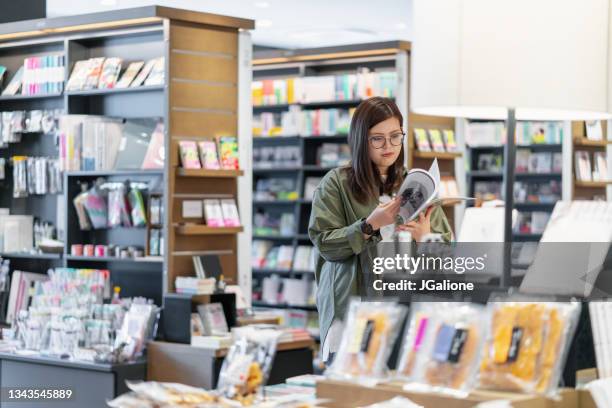 junge frau liest eine zeitschrift in einem geschäft - buchhandlung stock-fotos und bilder