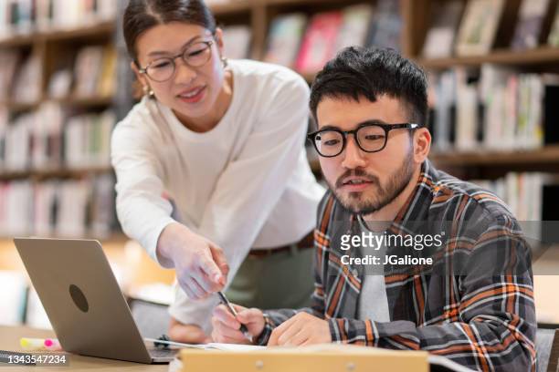 professor talking to a student in a library - japan training session stock pictures, royalty-free photos & images