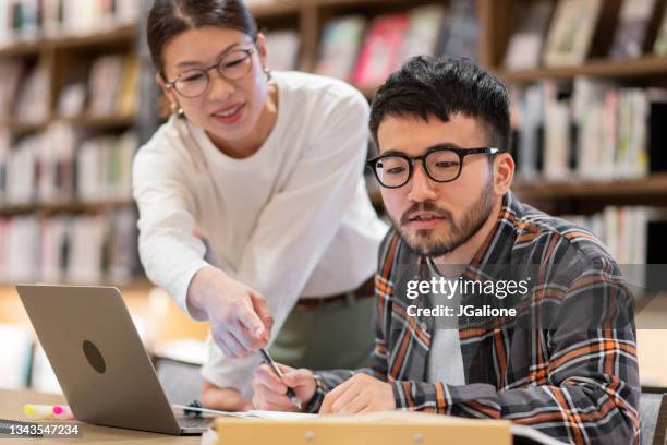 professor talking to a student in a library - 東洋民族 個照片及圖片檔