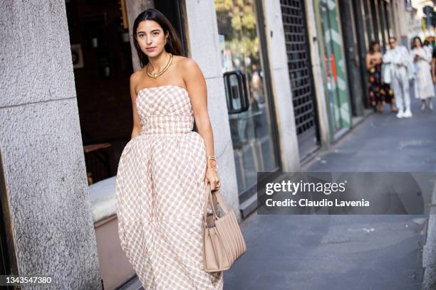 Bettina Looney, wearing a checked maxi dress and beige bag, poses ahead of the Max Mara fashion show during the Milan Fashion Week - Spring / Summer...