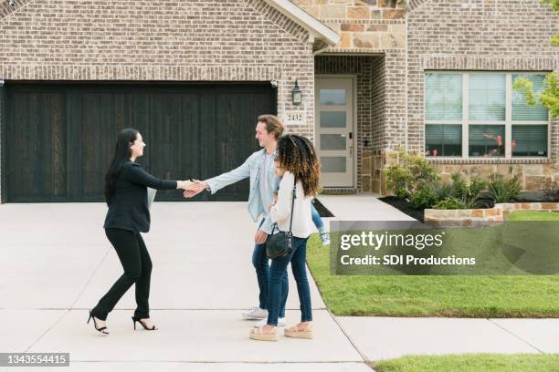 female real estate agent shakes hands with couple - ethnic millennial real estate stockfoto's en -beelden