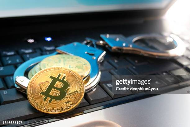 bitcoin-münzen und handschellen liegen auf der tastatur des laptops. - ico stock-fotos und bilder