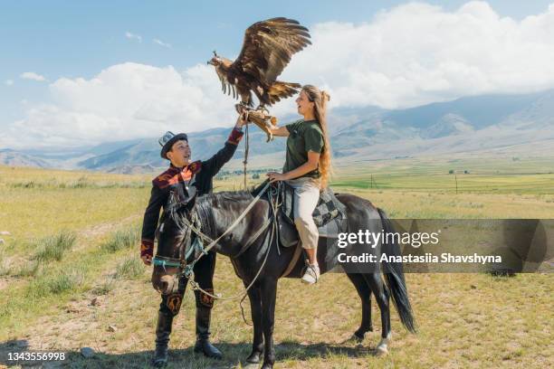 mujer viajera explorando las antiguas tradiciones con eagle hunter en las montañas de asia central - cetrería fotografías e imágenes de stock