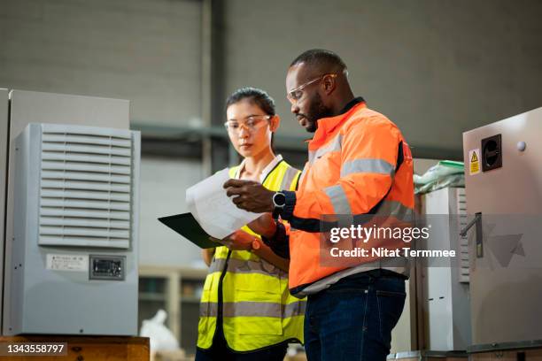 relationship working environment affects employee performance in the manufacturing industry. chief african and female solar energy engineers having a discussion about solar cell storage batteries workflow. - werk in uitvoering stockfoto's en -beelden