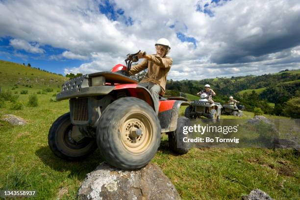 senior male driving quad bike in green rolling hills - backlight　green ストックフォトと画像