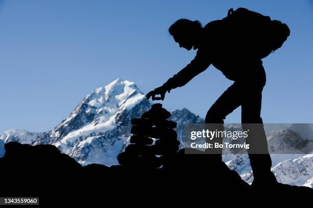 mountaineer making a cairn in front of mt.cook - bo tornvig photos et images de collection