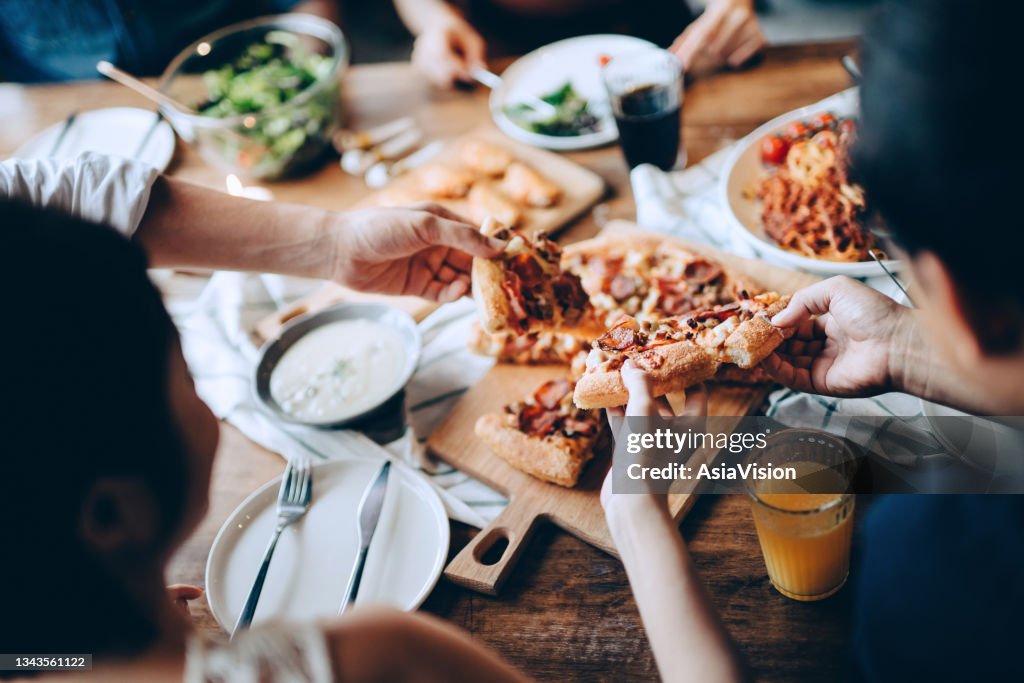 Primer plano de un joven grupo de amigos que pasan y sirven comida mientras disfrutan juntos. Se divierten, charlan y se dan un festín con comida y bebidas en la cena.