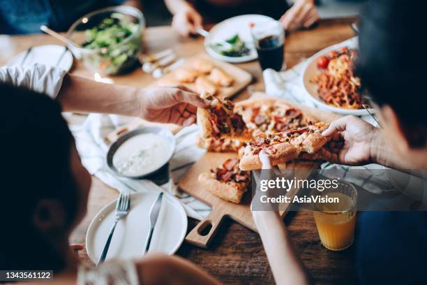 close up of a young group of friends passing and serving food while enjoying together. they are having fun, chatting and feasting on food and drinks at dinner party - food stockfoto's en -beelden