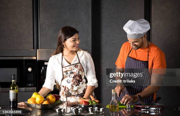 coppia che si diverte mentre cucina il cibo in cucina - indian couple foto e immagini stock