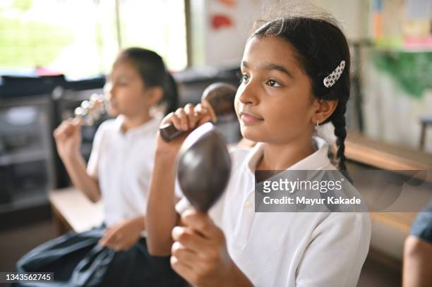 children in school uniform playing music with maracas in school - maracas fotografías e imágenes de stock