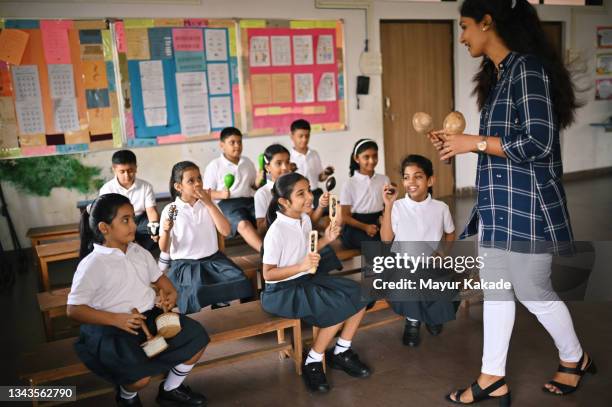 teacher teaching children in school uniform to play music with maracas in school - indian music 個照片及圖片檔