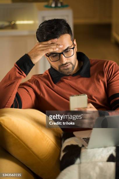 man feeling depressed on receiving bad news using phone - emotional stress stock pictures, royalty-free photos & images