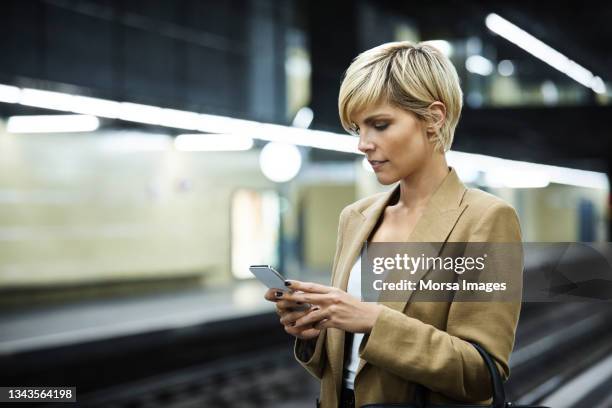 businesswoman using mobile phone at subway station - southern european stock pictures, royalty-free photos & images