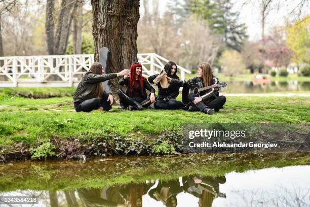 celebratory toast by smiling metalhead friends having park picnic with guitar - heavy metal guitarist stock pictures, royalty-free photos & images