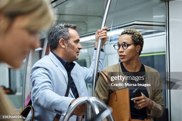 colleagues discussing in subway train - man woman train station stockfoto's en -beelden