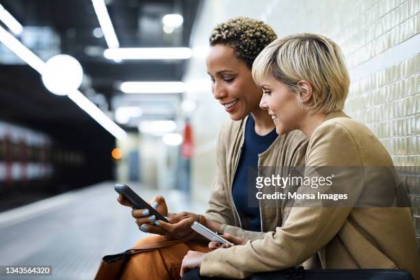 businesswomen using smart phone at subway station - gedeelde mobiliteit stockfoto's en -beelden