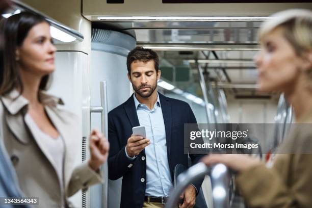 male professional using smart phone in train - smartphone im zug stock-fotos und bilder