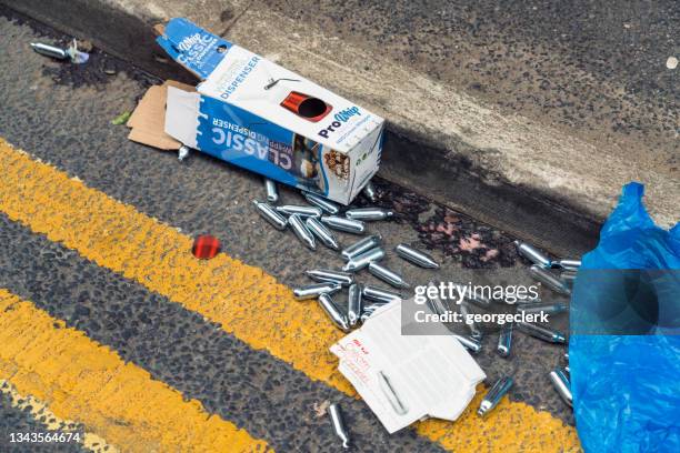nitrous oxide canisters discarded on the street - canister stock pictures, royalty-free photos & images