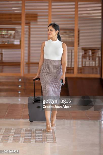 elegant businesswoman walking through a hotel lobby with luggage - star style lounge imagens e fotografias de stock