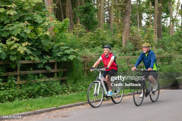 couple cycling down a country road - e bike stock pictures, royalty-free photos & images