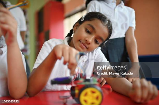 school girl making wiring connections in a  robot model in school - remote controlled car stockfoto's en -beelden