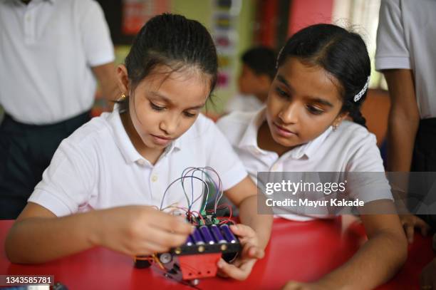 school girl making wiring connections in a  robot model in school - india robot stockfoto's en -beelden