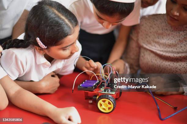 teacher and students making wiring on the circuit board and building a remote controlled car - india robot stockfoto's en -beelden