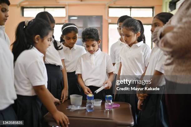 school girl showing science experiment to her classmates in school - school students science stock pictures, royalty-free photos & images