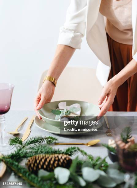 weihnachtsfeier: eine anonyme frau richtet den weihnachtstisch ein - weihnachtstisch stock-fotos und bilder