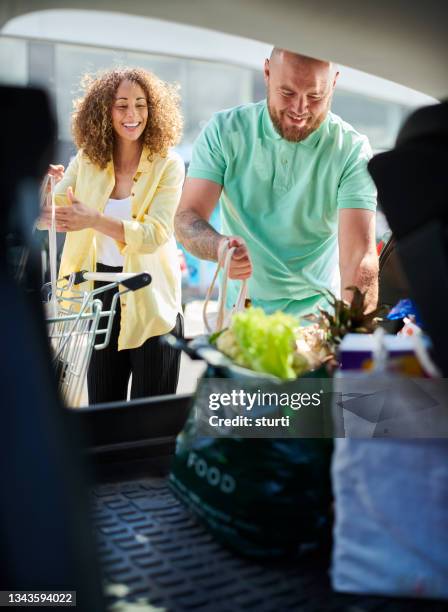 cargando el coche en el supermercado - carro supermercado fotografías e imágenes de stock