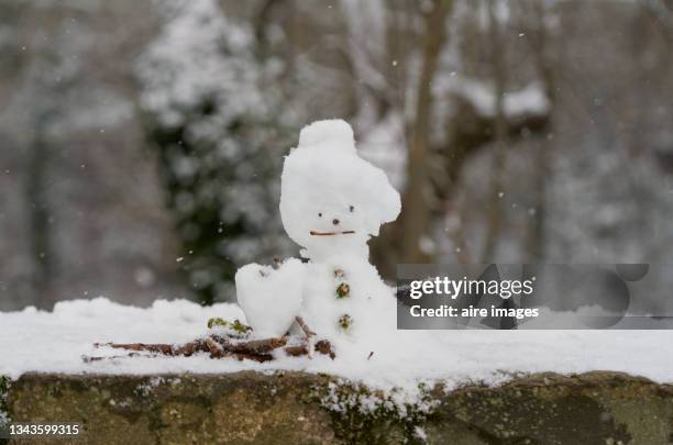 snowman and tree branches made on the wall of the city park on a snowy day - park city background stock pictures, royalty-free photos & images