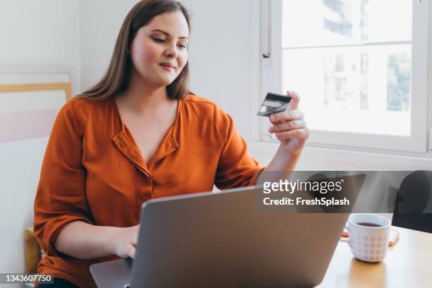 mujer con sobrepeso que compra en línea usando su computadora portátil, escribiendo la información de pago - chubby credit fotografías e imágenes de stock