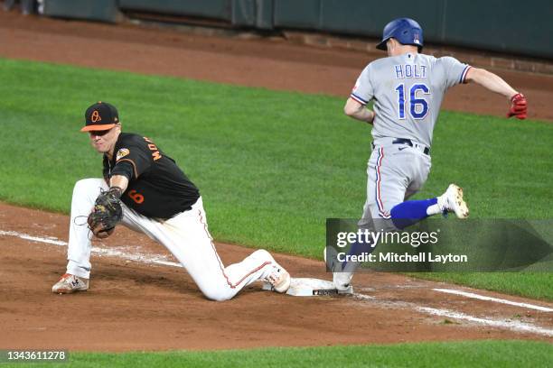 Brock Holt of the Texas Rangers tries to beat the throw to Ryan Mountcastle of the Baltimore Orioles during a baseball game at Oriole Park at Camden...