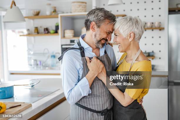 romantic mature couple, dancing in the kitchen - couple dancing at home stockfoto's en -beelden