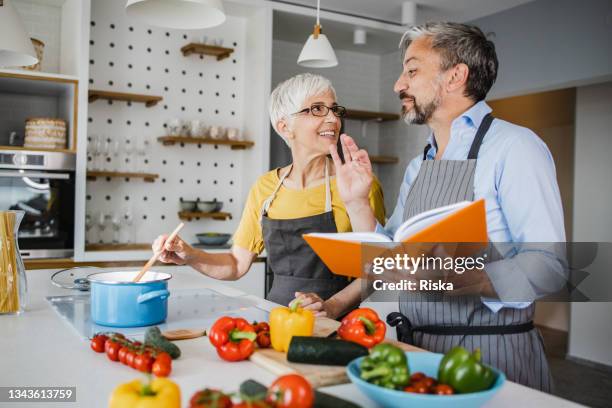 reifes paar bereitet das abendessen zu hause vor - middle aged couple cooking stock-fotos und bilder